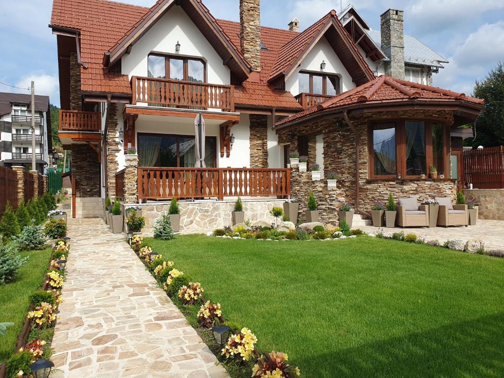 a house with a green lawn in front of it at Poiana Golf Chalet in Buşteni