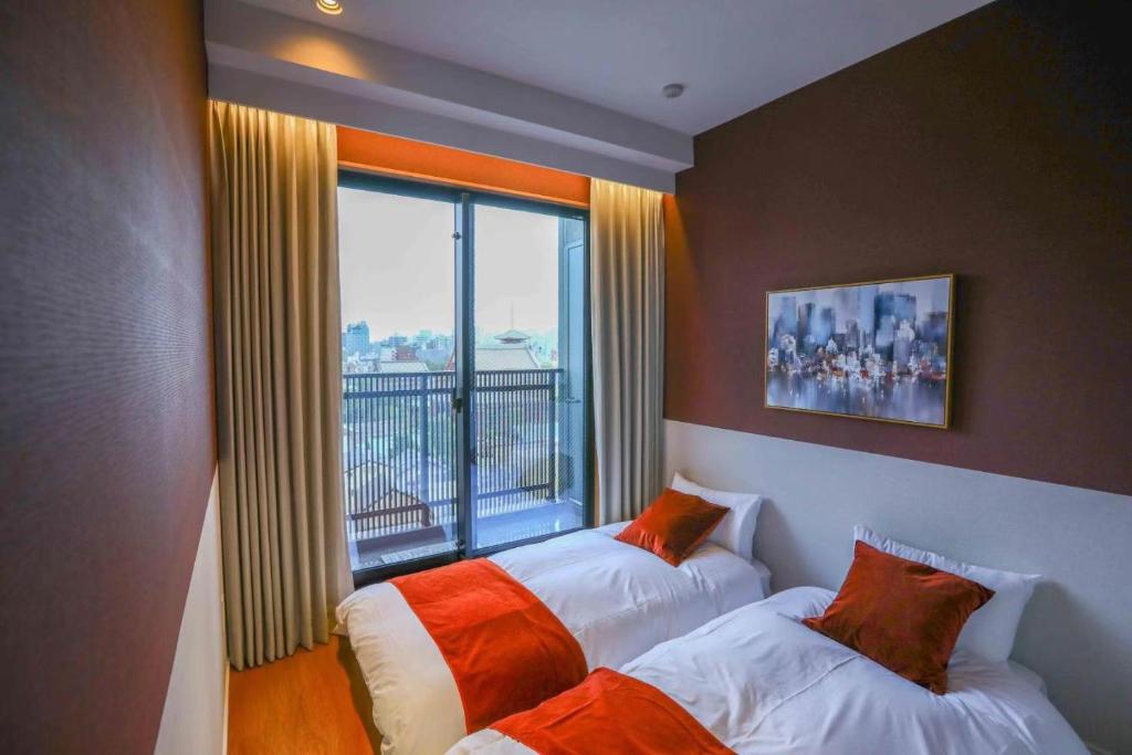 twee bedden in een kamer met een groot raam bij the Moto Hotel Asakusa in Tokyo