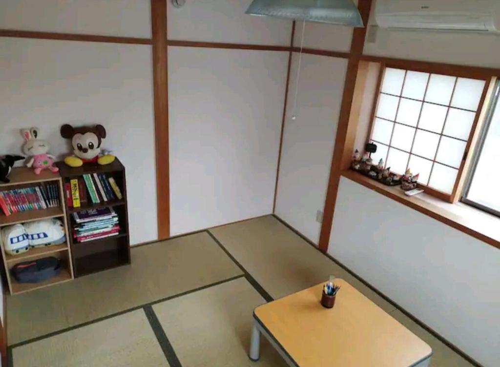 a room with a table and a book shelf at IIIハウス　ひらパーからすぐの３階建て一軒家　全寝室エアコン新調　wifi完備　旅行&ビジネス大歓迎 in Hirakata