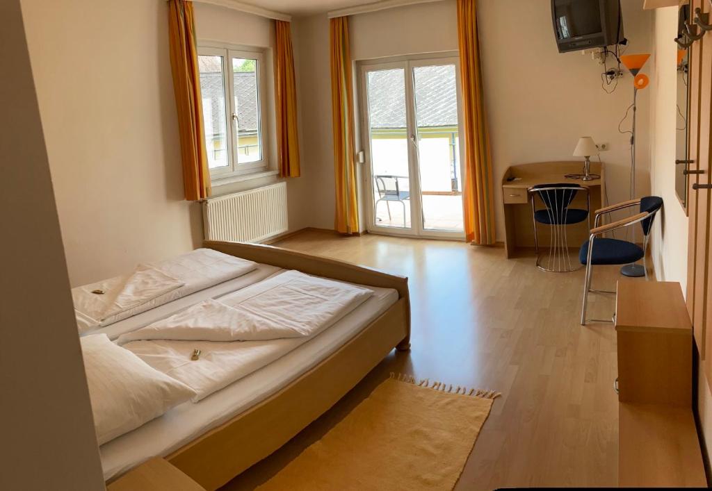 Schlafzimmer mit einem Bett, einem Schreibtisch und Fenstern in der Unterkunft Gasthof zum Goldenen Löwen - Nebenhaus in Ehrenhausen