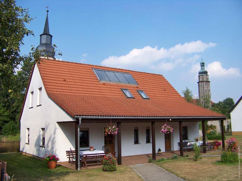 ein weißes Haus mit einem orangenen Dach und einer Kirche in der Unterkunft Haus Fledermaus in Bad Schmiedeberg