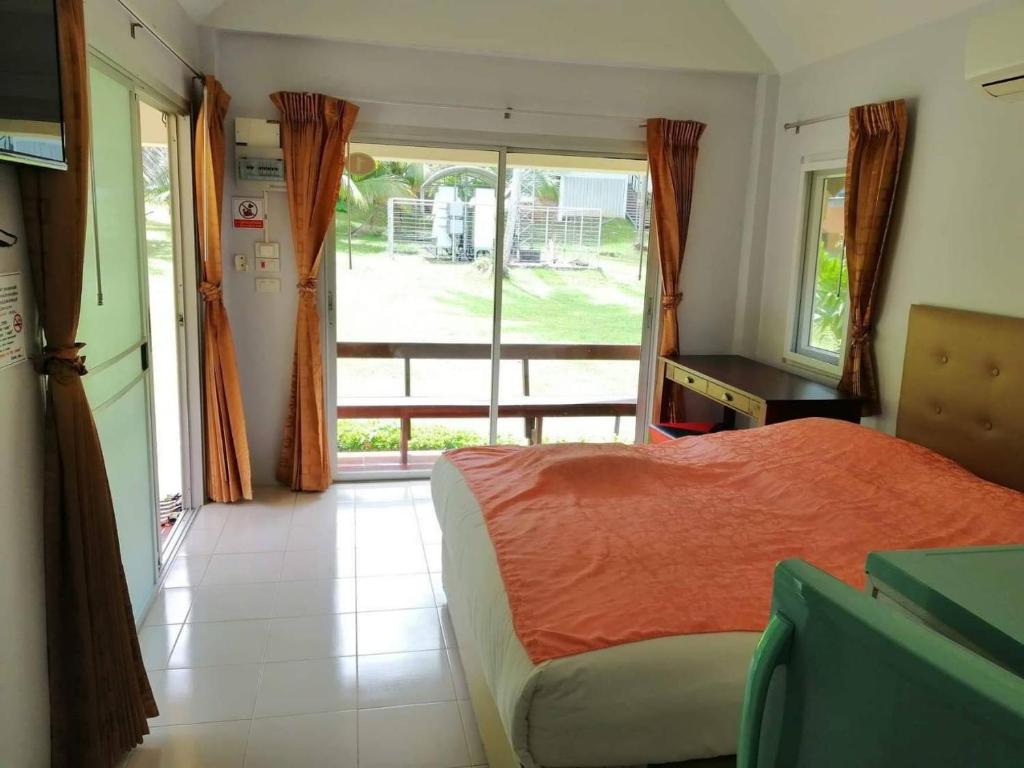 een slaapkamer met een bed en een groot raam bij เกาะช้างรักดี รีสอร์ท 