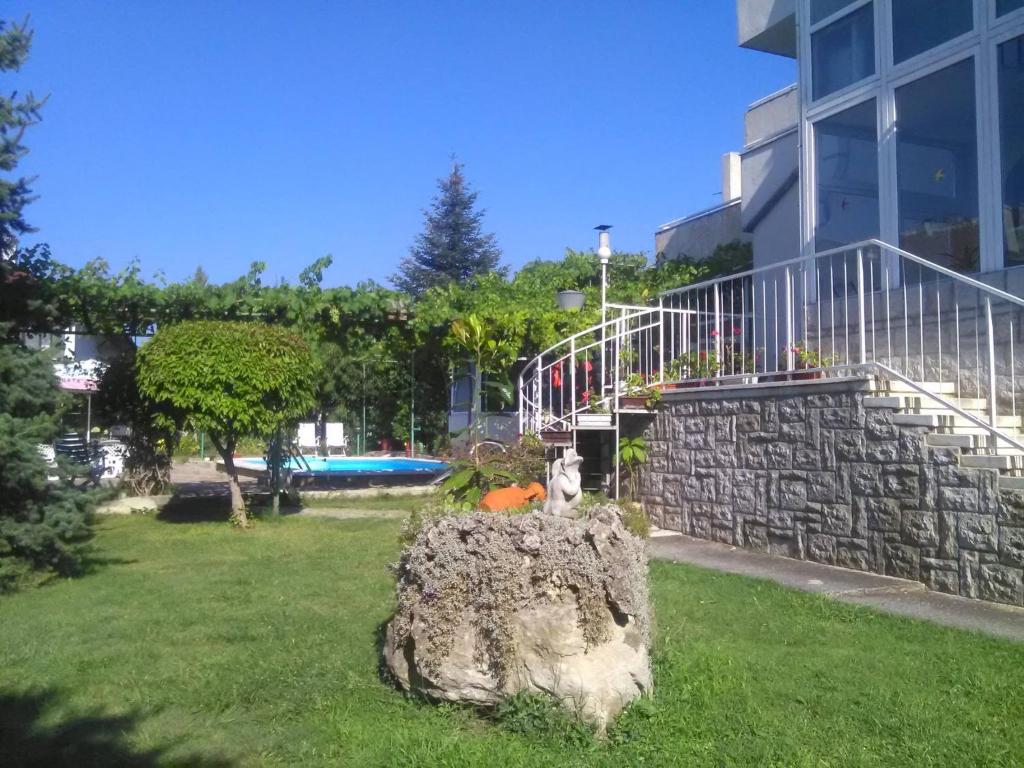 a rock in the grass in front of a building at Family Hotel California - Varna in Varna City