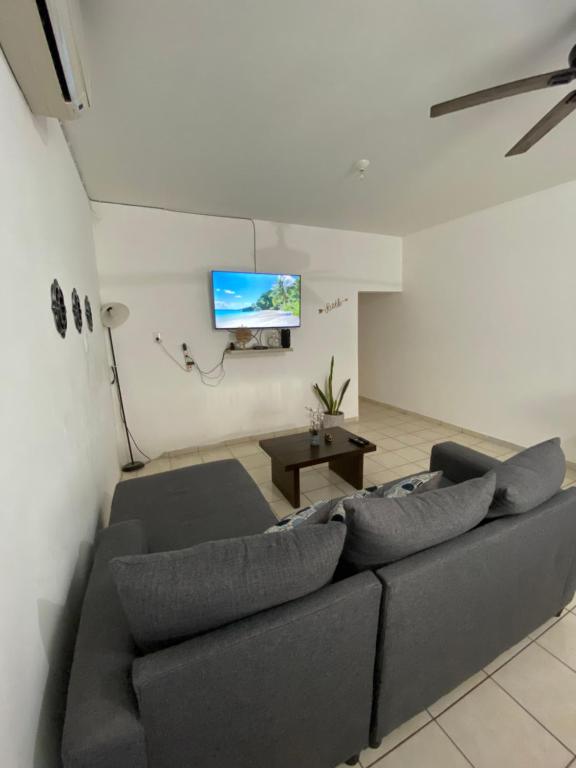 uma sala de estar com um sofá e uma televisão de ecrã plano em Casa a 5 minutos del mar em Mazatlán