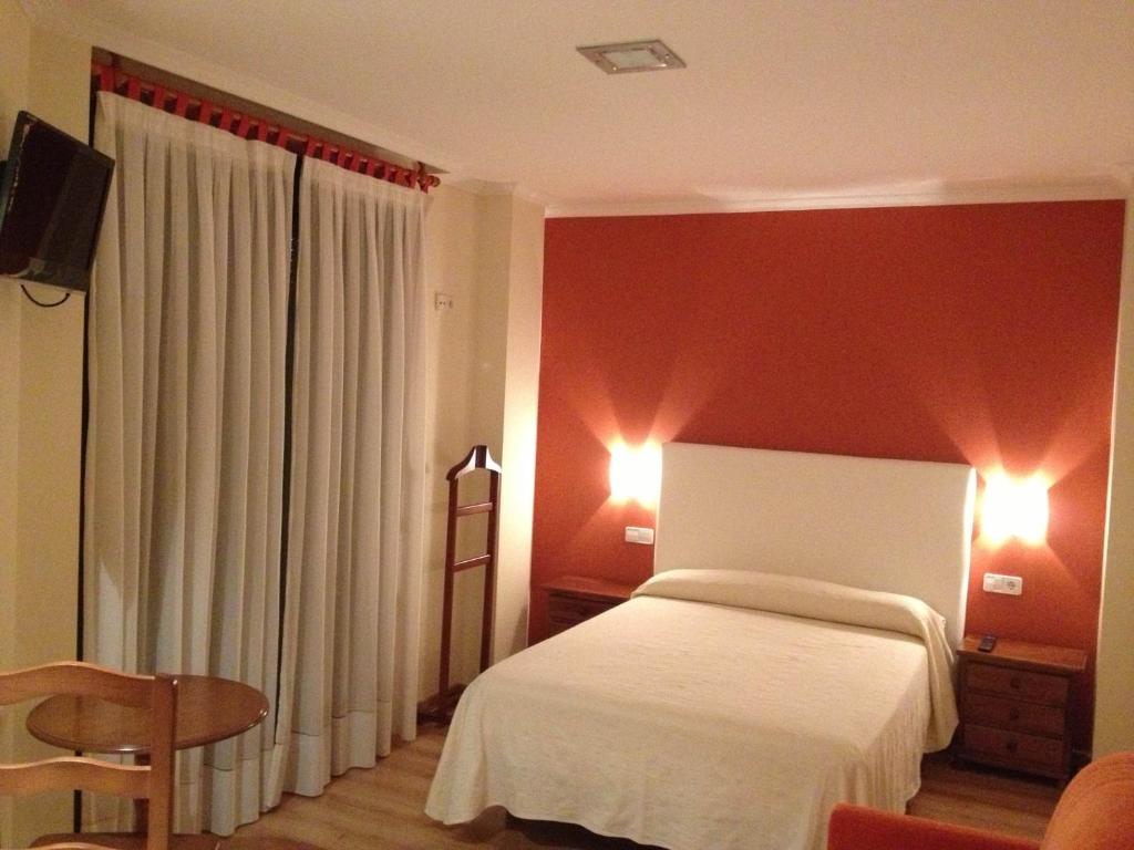 1 dormitorio con cama blanca y pared roja en Hostal Santa Baia, en Ribadumia