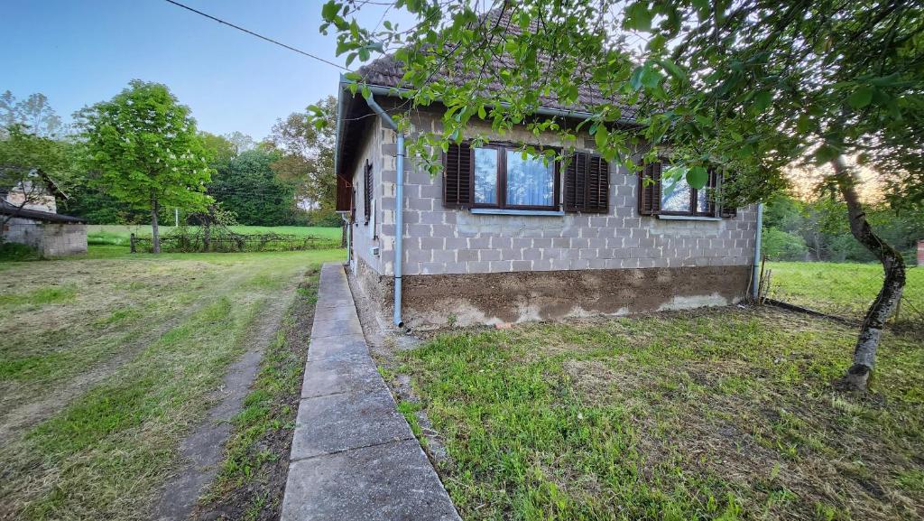 uma casa de tijolos com duas janelas e um quintal em Kuća djeda Ive 