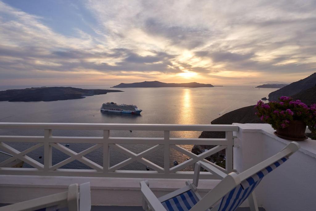 um navio de cruzeiro na água ao pôr do sol em Amphitheater Cave Houses em Fira