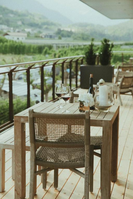 a wooden table with wine glasses on a balcony at Solterra Poolhouse 1 in Tesimo