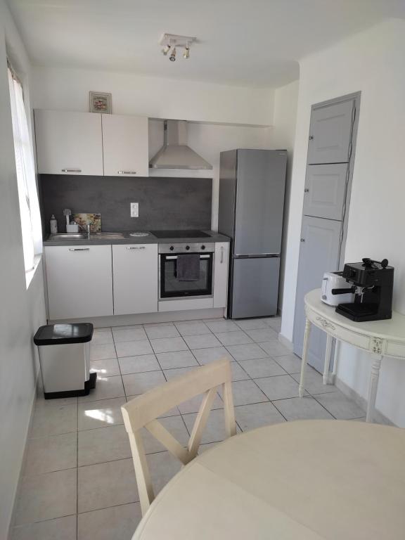 - une cuisine avec des appareils blancs, une table et une chaise dans l'établissement Appartement calme et cosy, à Avignon