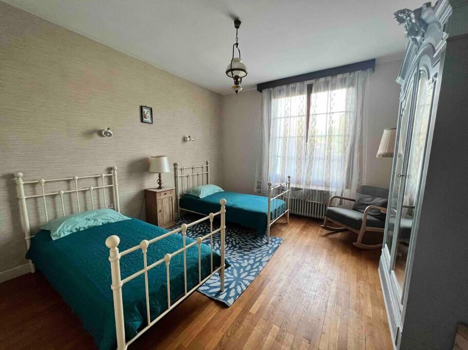 1 dormitorio con 2 camas, silla y sofá en Maison de la petite fourmy, en Saint-Sulpice-les-Feuilles