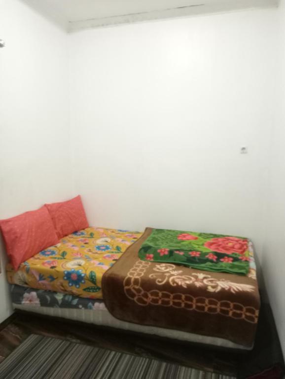 a small bed sitting in a corner of a room at Homestay putih Ciwidey in Ciwidey