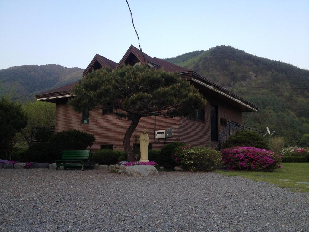 a house with a tree and a bench in front of it at Gabriel Villa in Jeongseon