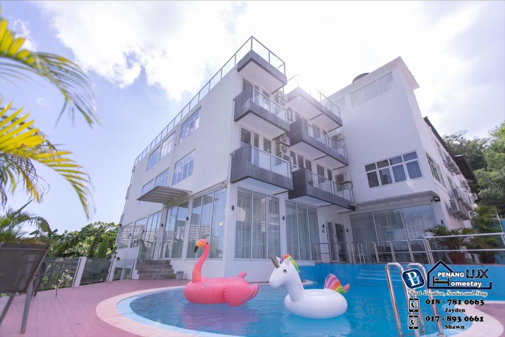 a house with two inflatable flamingos in a swimming pool at 15BR SwimmingPool Villa Golf View Snooker BBQ in Bayan Lepas