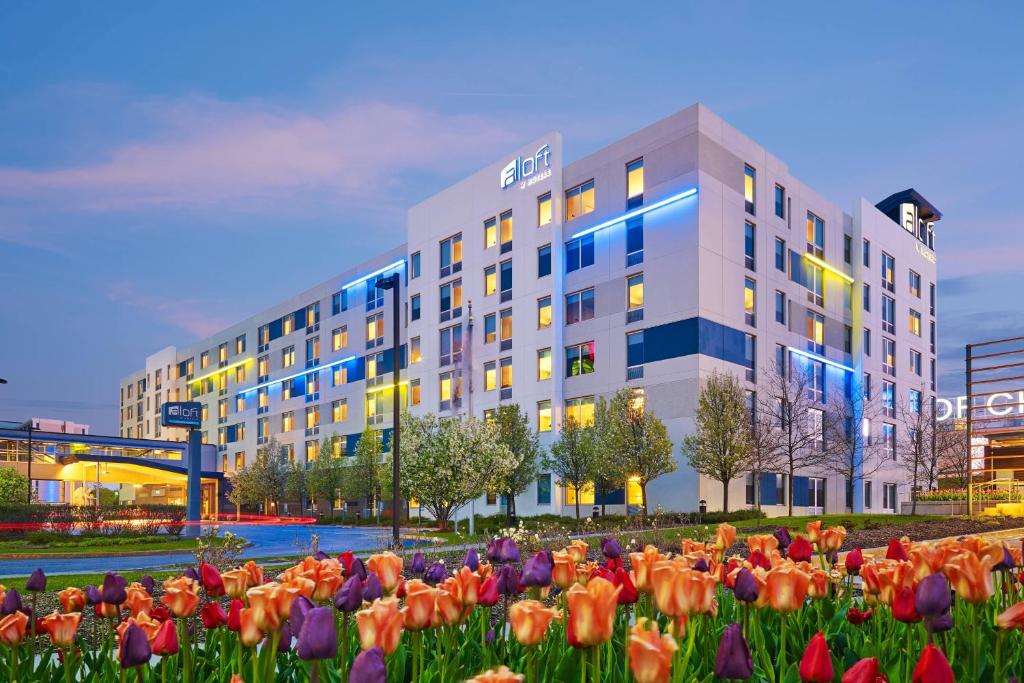 a large building with flowers in front of it at Aloft Chicago O'Hare in Rosemont