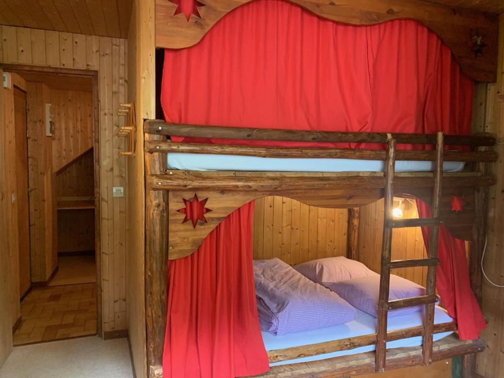 a bedroom with two bunk beds with red curtains at Le p&#39;tit coin montagne 3 in Bonneval-sur-Arc