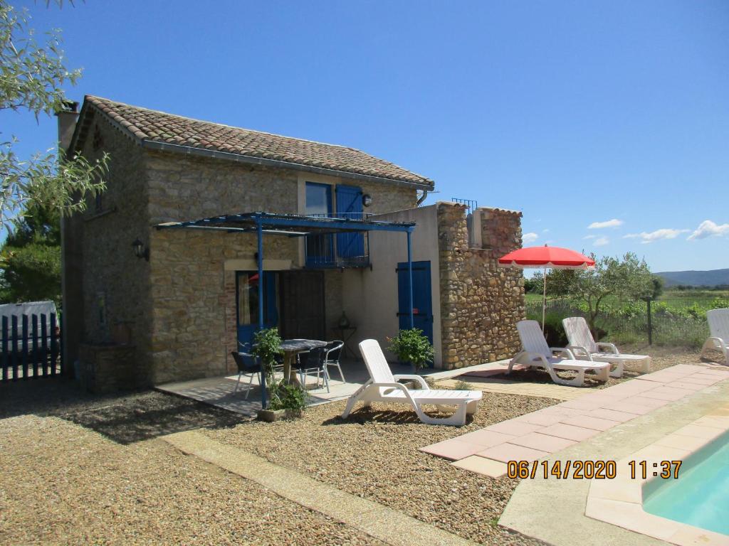 un patio avec une table, des chaises et un parasol dans l'établissement Le Mas du Sourdet, à Saint-Victor-de-Malcap