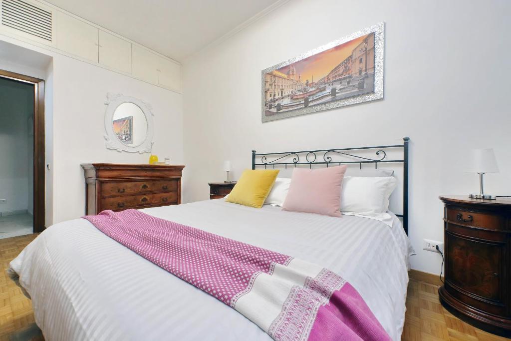 a bedroom with a large white bed with colorful pillows at Pigneto Cozy Flat in Rome