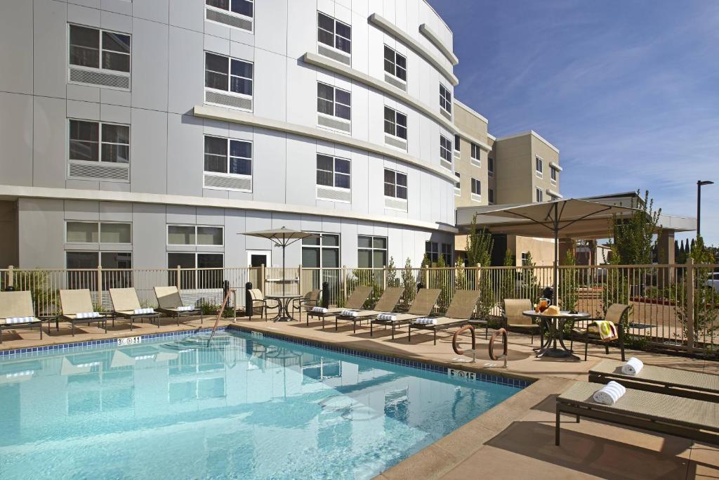 uma piscina de hotel com cadeiras e um edifício em Courtyard by Marriott Sunnyvale Mountain View em Sunnyvale