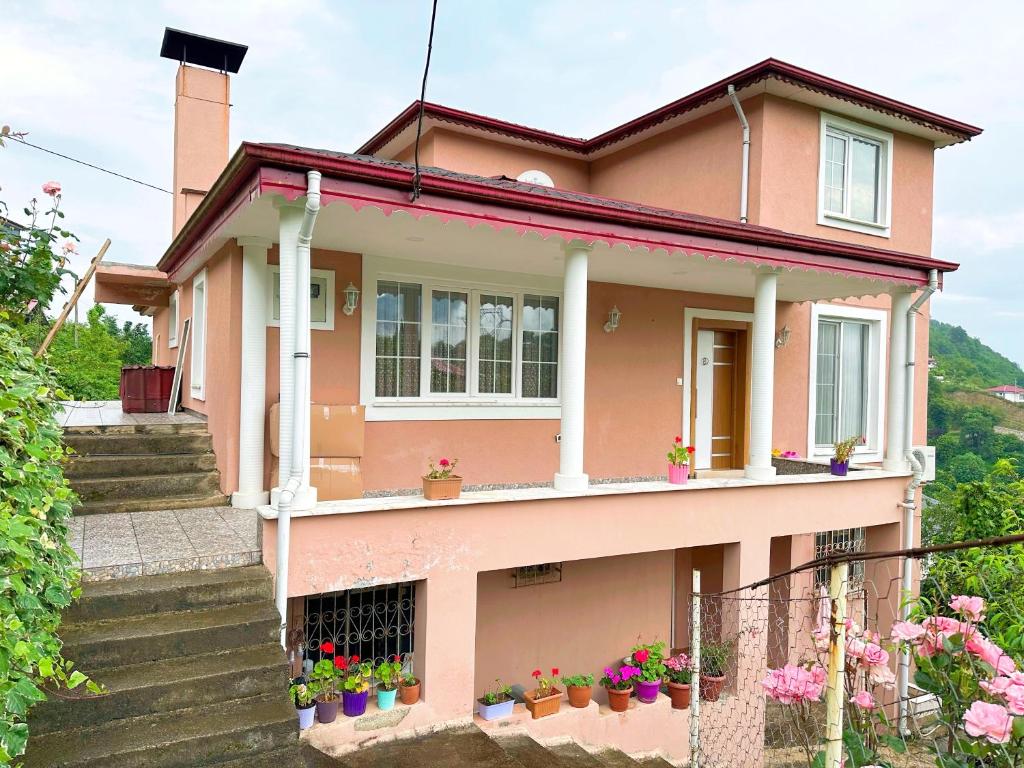 特拉布宗的住宿－COUNTRY HOME，粉红色的房子,上面有盆栽植物