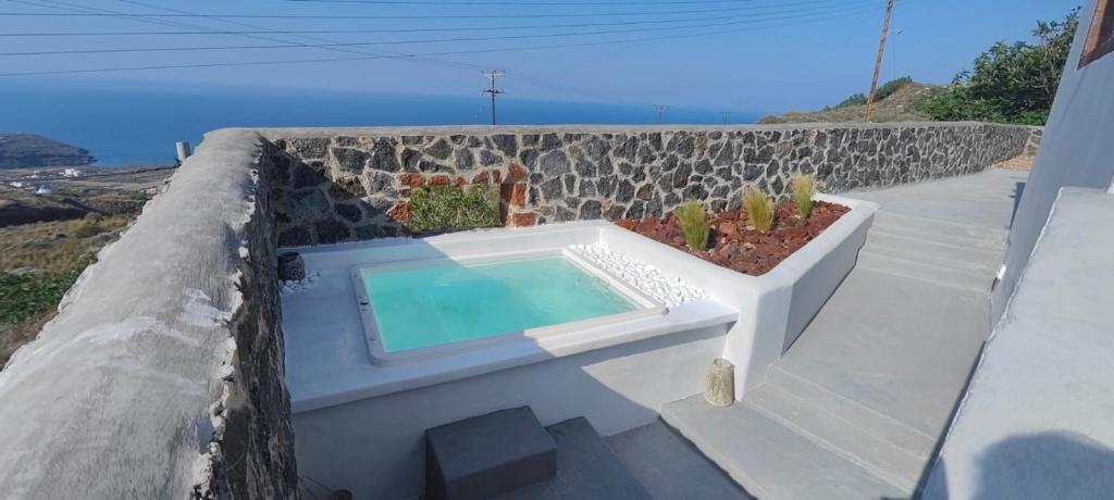 une piscine dans un mur de retenue avec un cactus dans l'établissement Alios villa, à Imerovigli