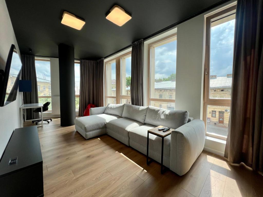 een woonkamer met een witte bank en grote ramen bij Old City FORUM Apartments in Lviv