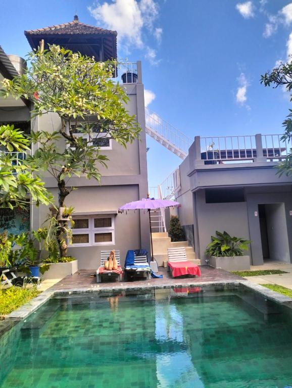 een vrouw zittend op een stoel naast een huis met een zwembad bij The Island Bali in Seminyak