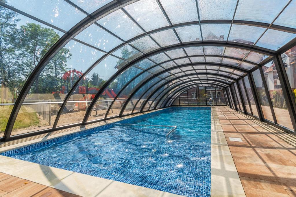an indoor swimming pool with a glass ceiling at Apartamenty Mierzeja NCNK Baltic Garden Sztutowo in Sztutowo
