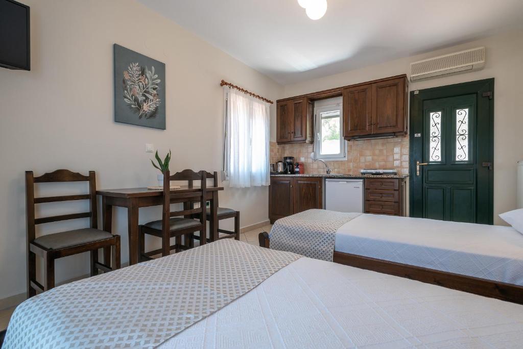a bedroom with two beds and a kitchen with a table at Amigdalies in Myrina