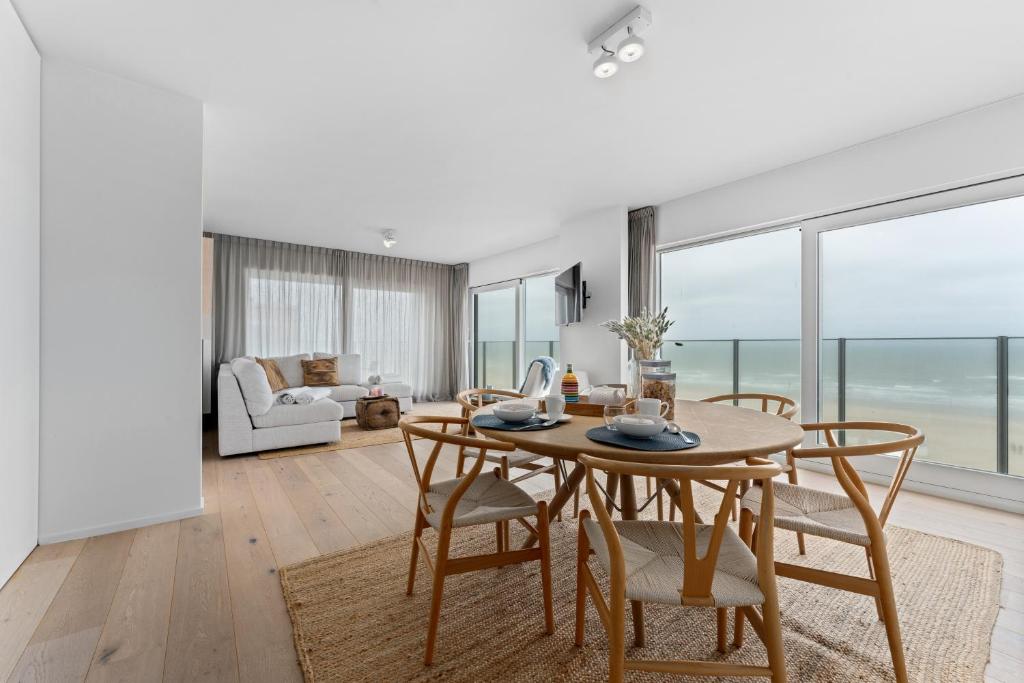 a dining room with a table and chairs with a view of the ocean at Seaflow-Holiday appartment with frontal sea view in Oostduinkerke