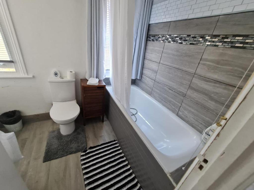 a bathroom with a tub and a toilet and a shower at Three bedroom House in London