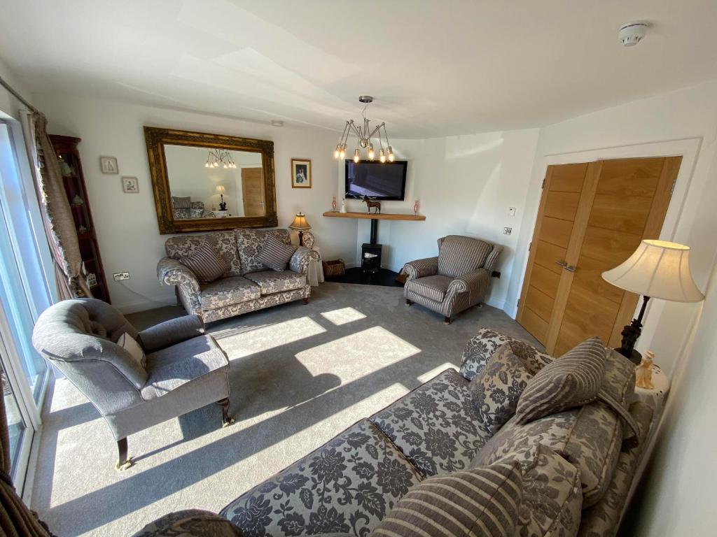 un soggiorno con divano, sedie e TV di Ardbrin Lodge a Dunadry