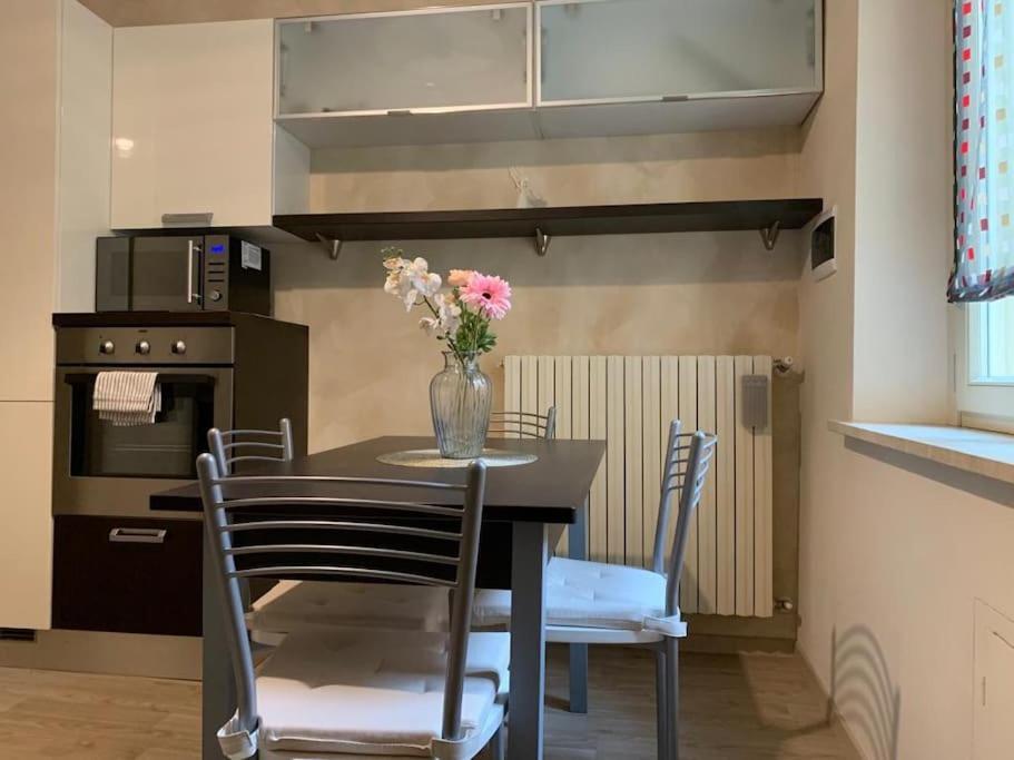 Una cocina con una mesa con un jarrón de flores encima. en Borgo San Silvestro 9, en Parma