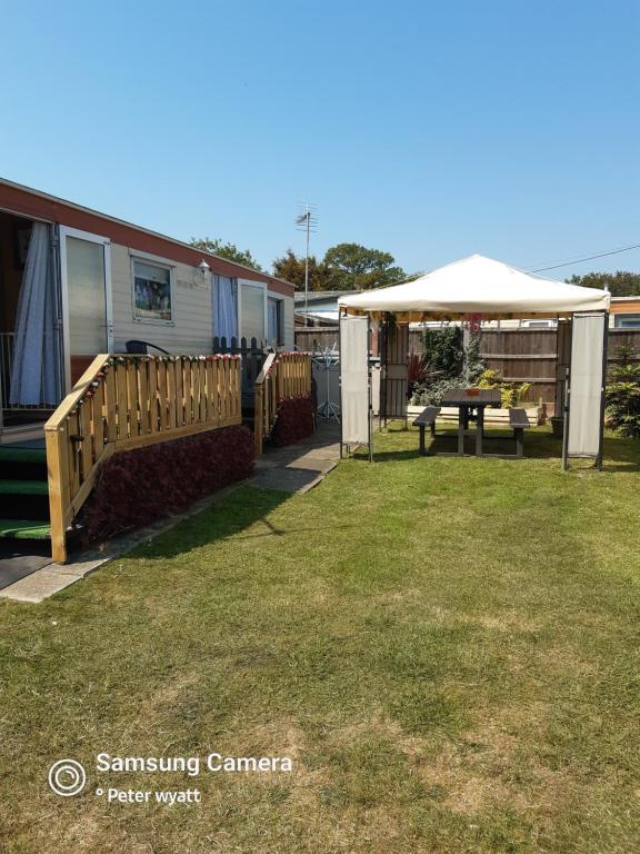 un patio trasero con una mesa de picnic y una tienda de campaña en Gina's Static caravan,118 Sandsgate en Hemsby