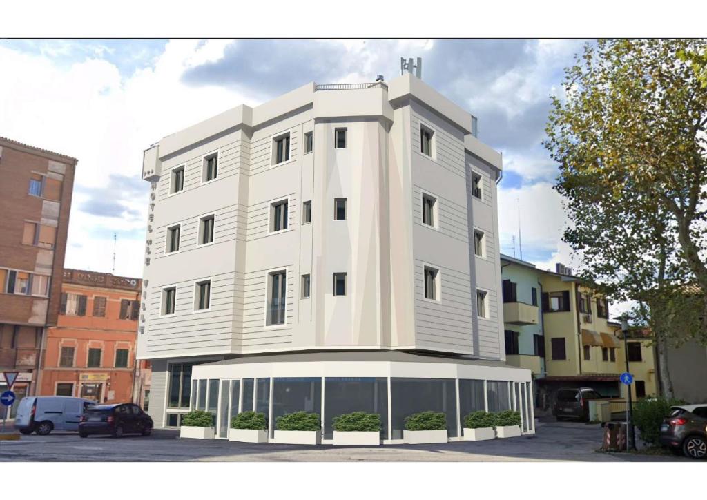 un grande edificio bianco in un parcheggio di Hotel De La Ville depandance di Hotel Augustus a Fano