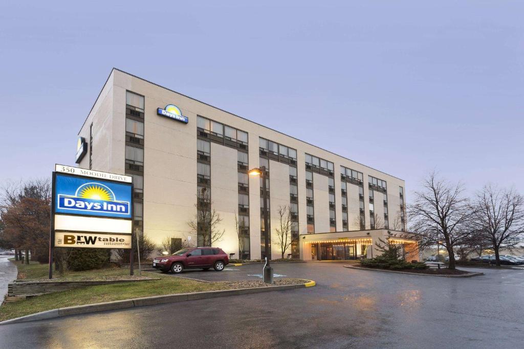 a building with a car parked in a parking lot at Days Inn by Wyndham Ottawa West in Ottawa