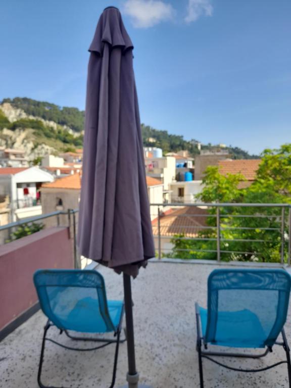 two chairs and an umbrella on a balcony at Bright top floor apartment! in Zakynthos Town