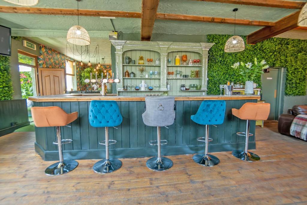 a kitchen with a bar with three stools at Entire Venue with Accommodation Sleeps up to 19 - Waterfall Country Escape Wales in Coelbren