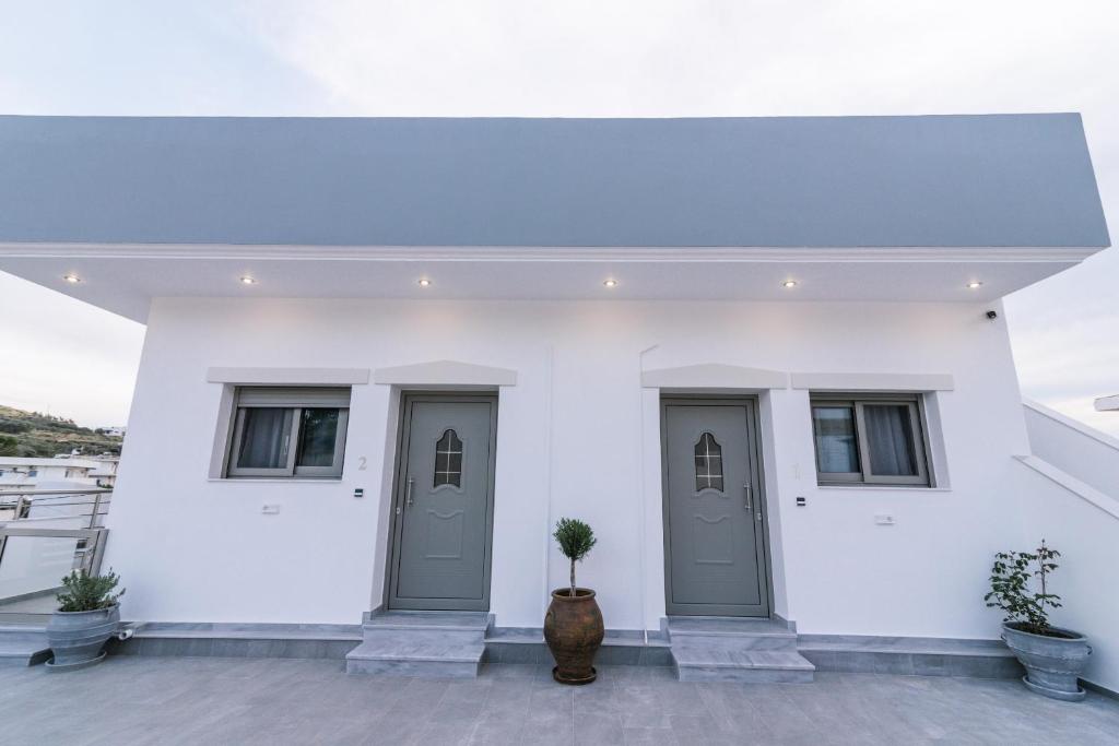 a white building with two doors and two windows at Lychnos apartments in Kamilari