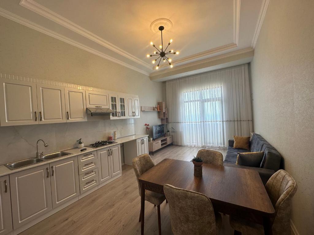 a living room with a table and a kitchen at Caspian Pearl Residence in Sumqayıt