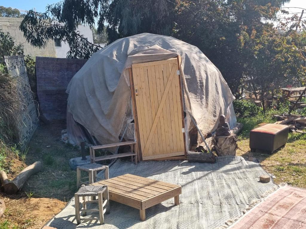 a yurt with a wooden door and a wooden stool at Dome of the heart in Pardes H̱anna
