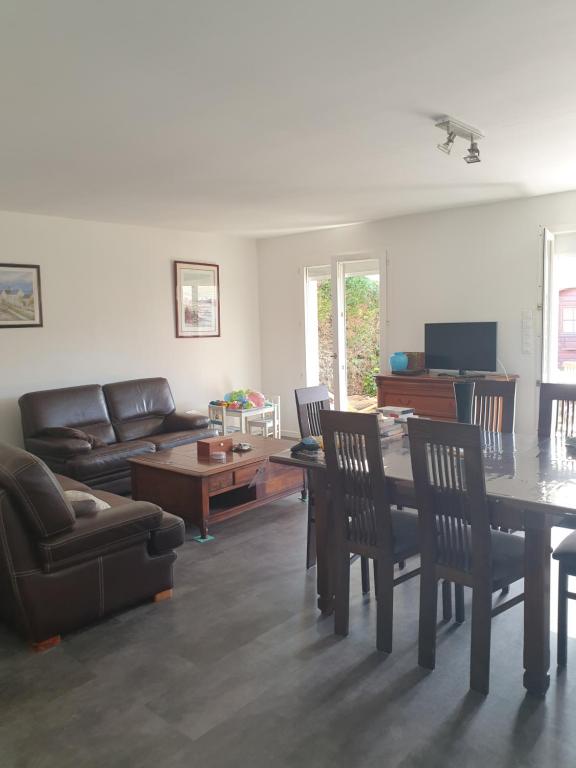sala de estar con sofá, mesa y sillas en LA ROCHELLE classé 3 étoiles, en Nieul-sur-Mer