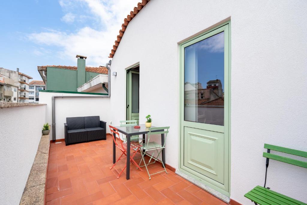 a balcony with a table and a green door at Ilda's Home - Big Families & Groups in Porto