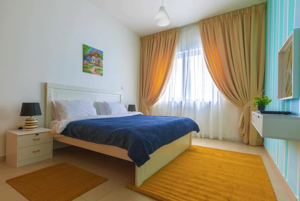 a bedroom with a bed with blue sheets and a window at GREAT 3 Bedroom Apartment Beach Front (Side View) in Abu Dhabi