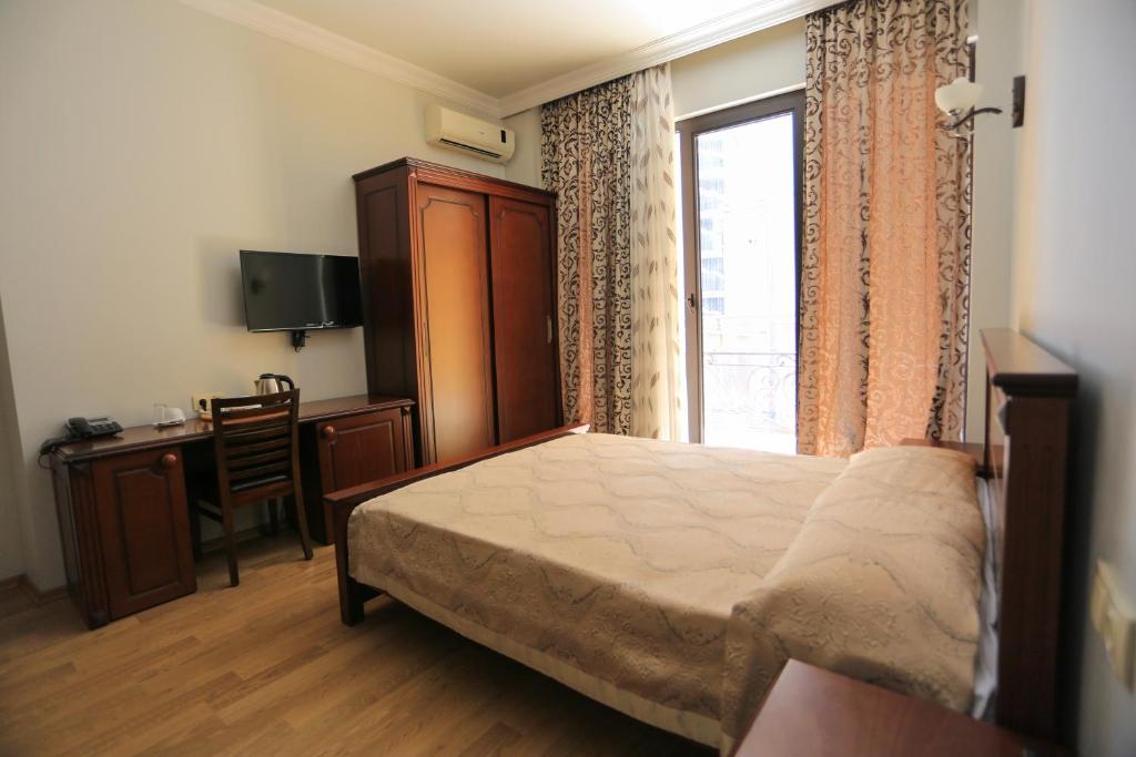 a bedroom with a bed and a desk and a window at Eiffel Hotel in Batumi
