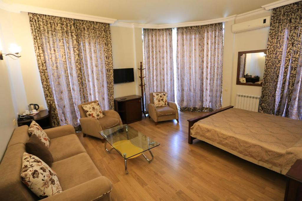 a living room with a bed and a couch and chairs at Eiffel Hotel in Batumi