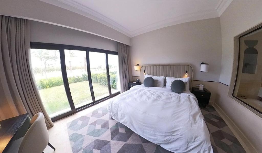 1 Bedroom Suite @ The address Golf Marassi Resort في العلمين: غرفة نوم بسرير كبير ونافذة كبيرة