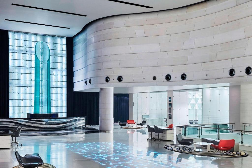 a lobby with chairs and tables in a building at Le Meridien New Delhi in New Delhi