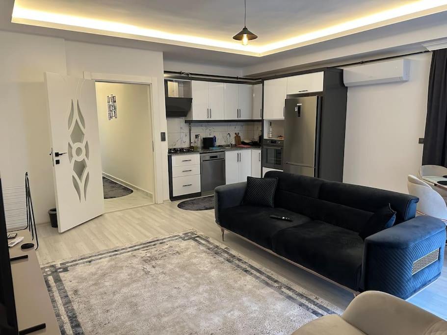 ein Wohnzimmer mit einem schwarzen Sofa und einer Küche in der Unterkunft Close to the beach (150 m.) and central locations in Antalya