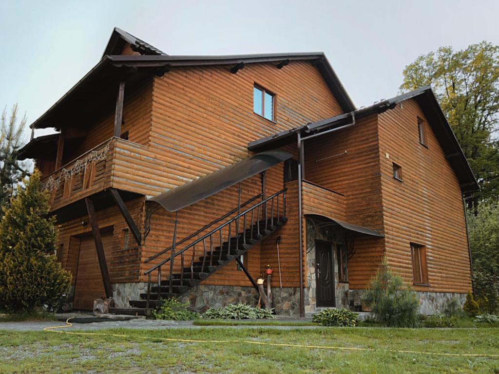 a large wooden house with a man standing in front of it at Darynka in Yaremche