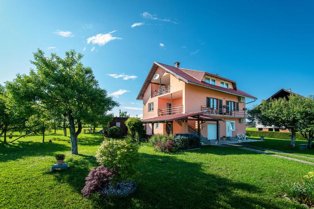 une grande maison dans une cour verdoyante avec des arbres dans l'établissement Emmy i Alice, à Josipdol